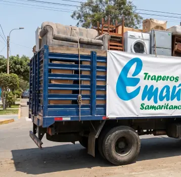 Camión de Traperos de Emaús cargado con donaciones y el logotipo de la institución.