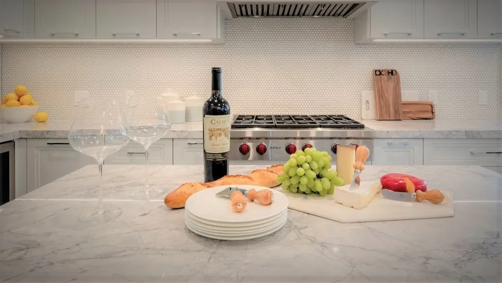 Image of Luxury kitchen interior design with marble island, wine, cheese board, and elegant furniture by KHD Homes.