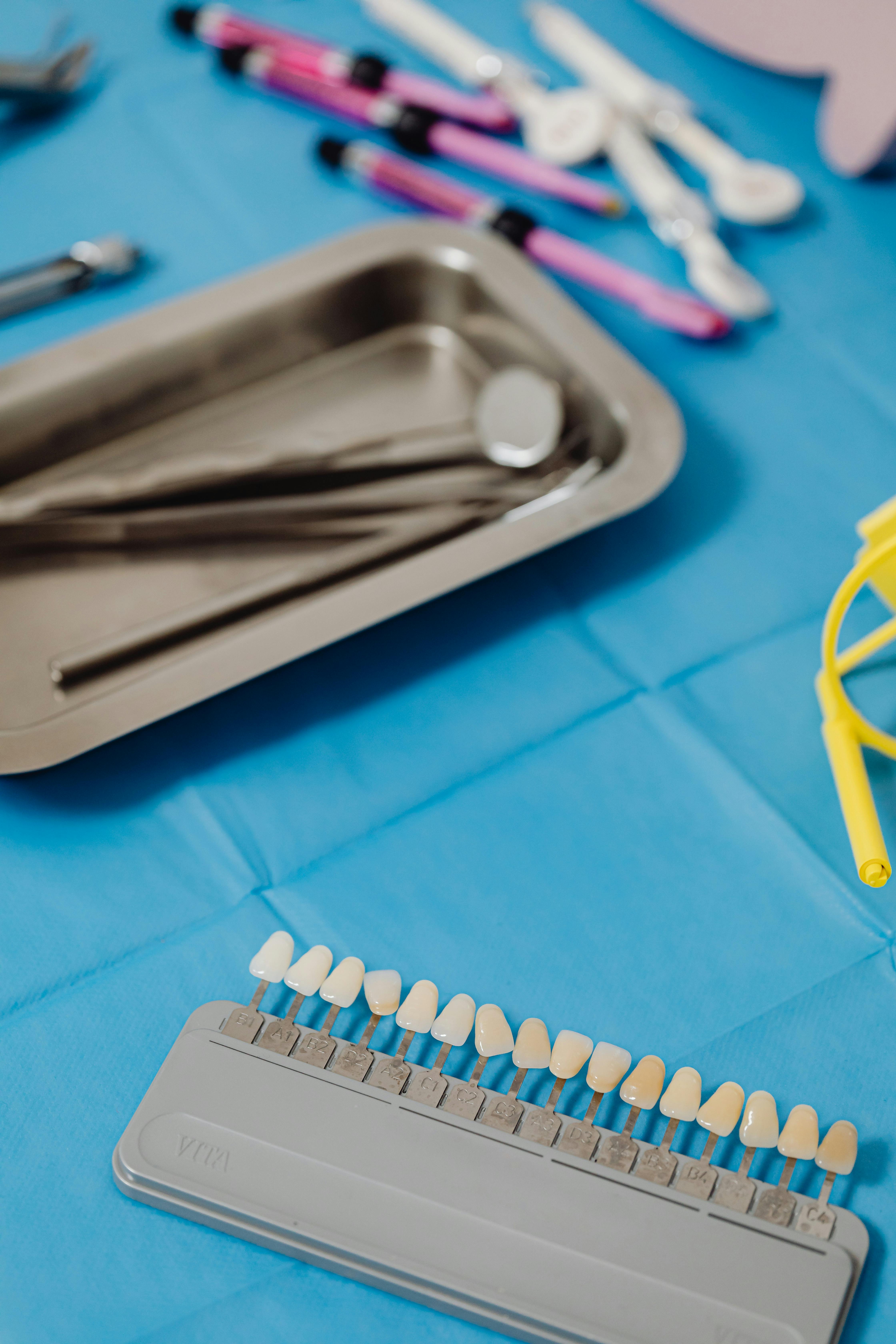A picture of Dental shade guide and instruments on blue clinical surface.