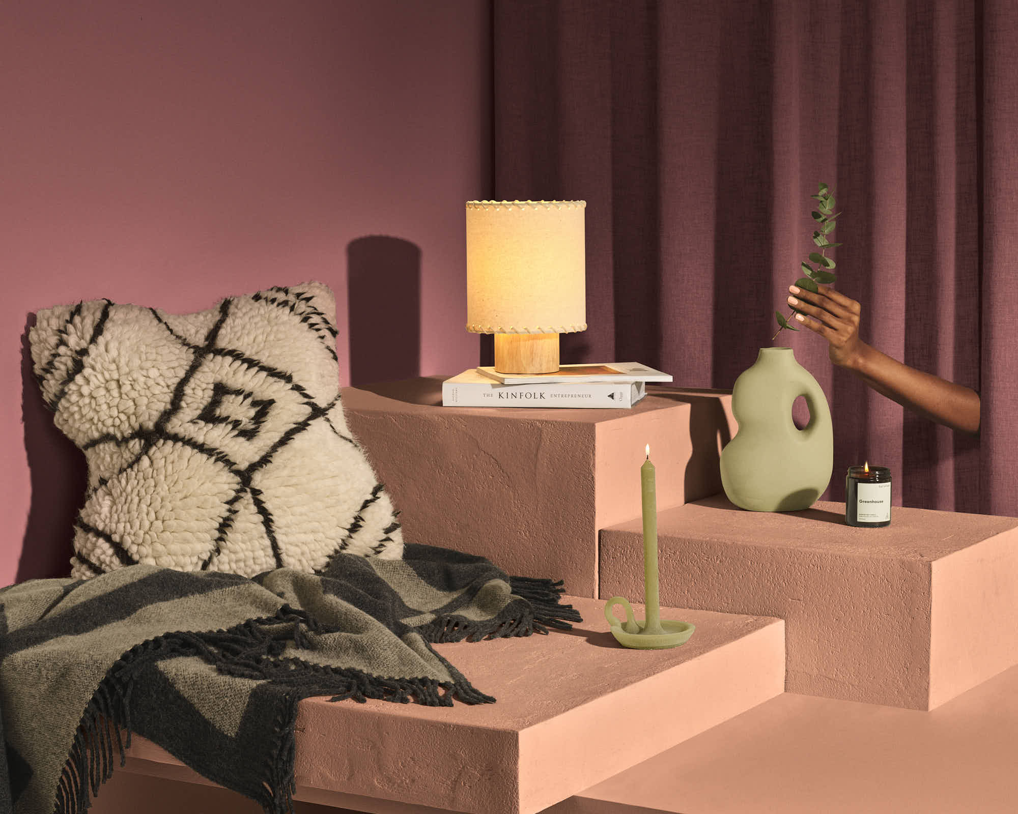 Modern home decor with textured pillow, pastel candle, unique vase, and soft lighting.