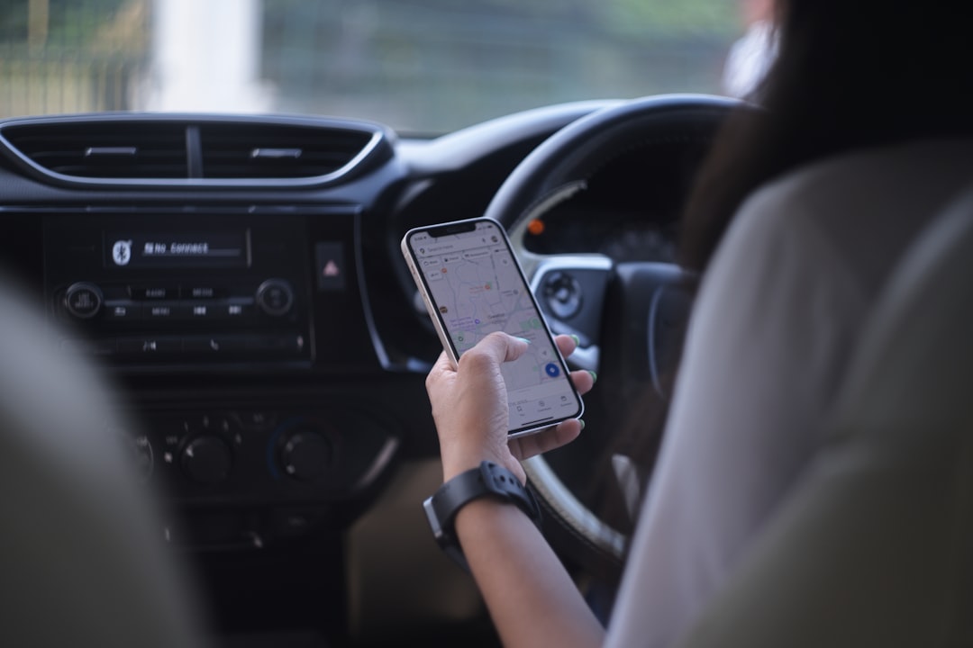 A woman holding a cell phone while driving a car