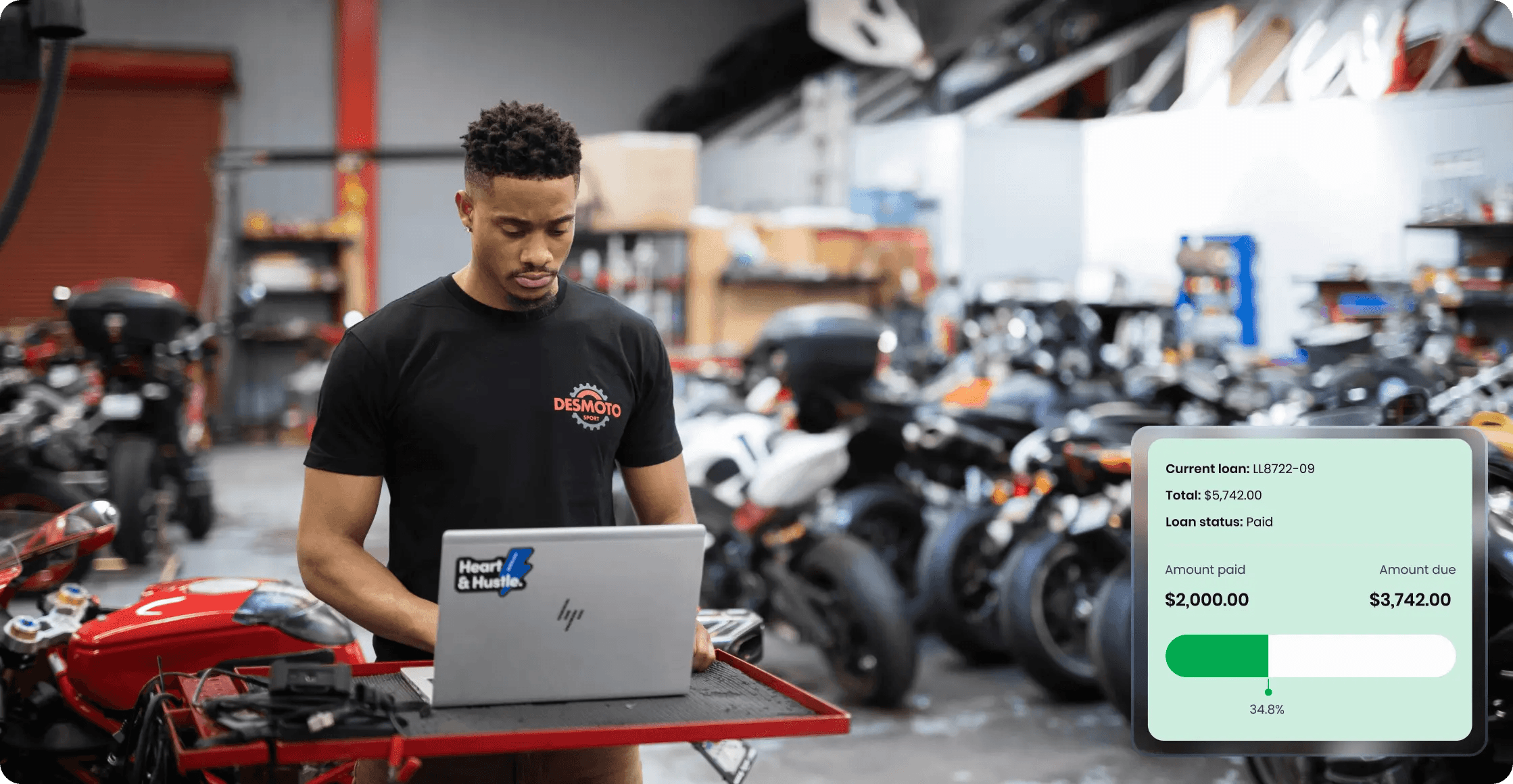 Business owner using a laptop in a workshop environment with a financial repayment interface overlaid, representing product impact on daily operations.