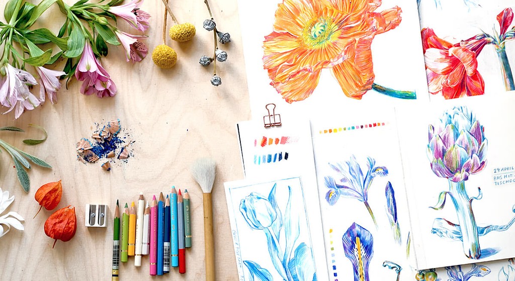 Foto eines Flatlays von Zeichenmaterial und botanischen Zeichnungen auf einem Tisch