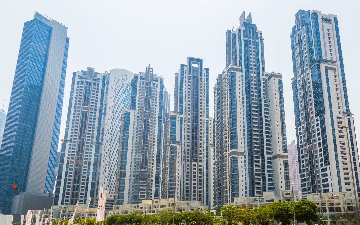 Business Bay skyline with glass skyscrapers, geometric designs, and greenery at the base of high-rise towers.