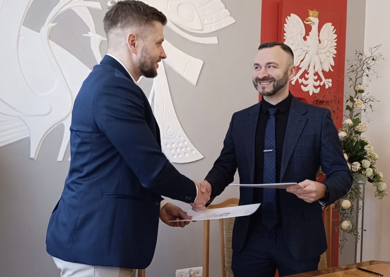 A woman with auburn hair and a gray coat over a white sweater, set against a neutral background, exuding a minimalist aesthetic.