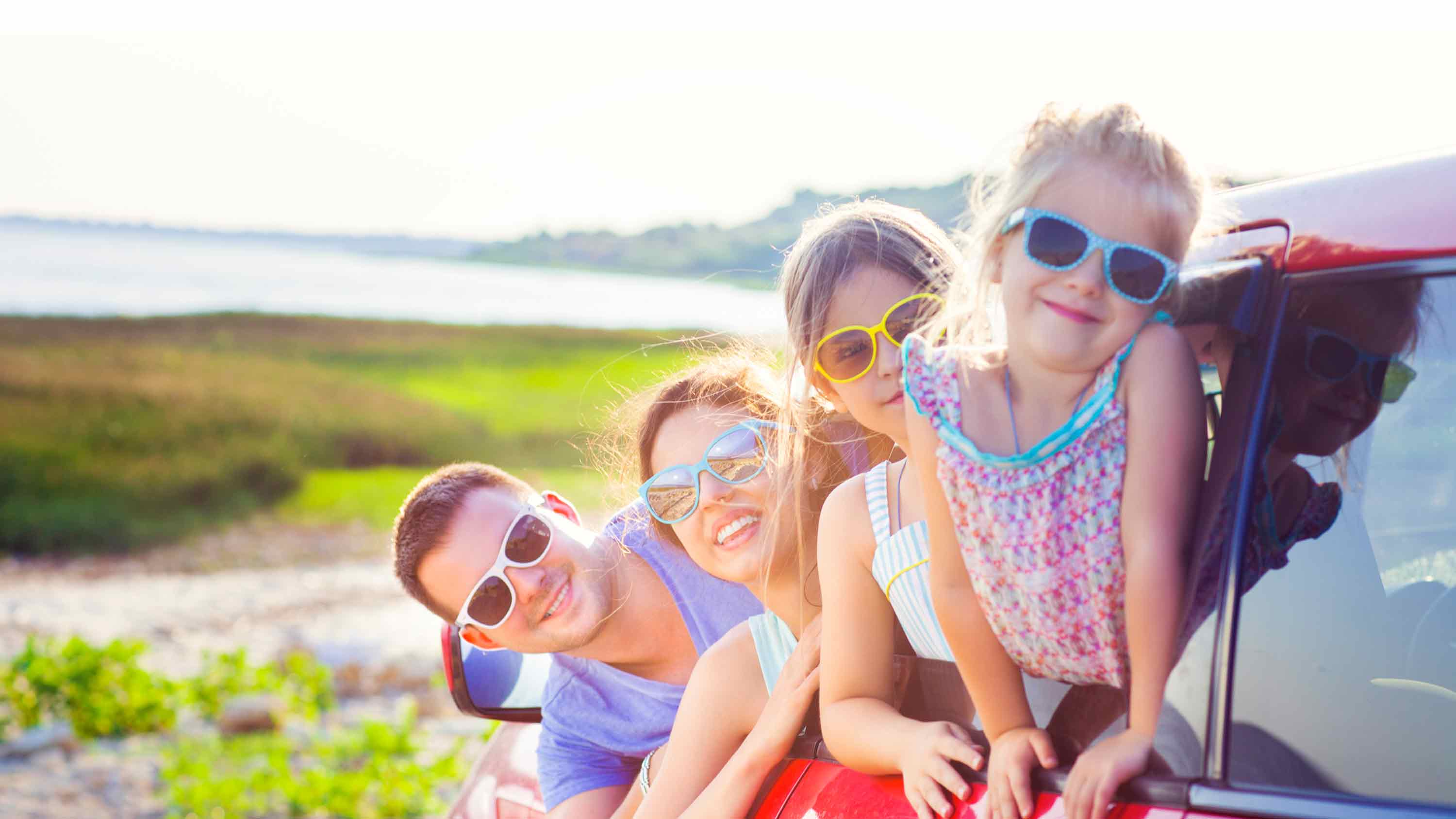 Head foto van familie met kinderen die uit de auto hangen met een landschap.