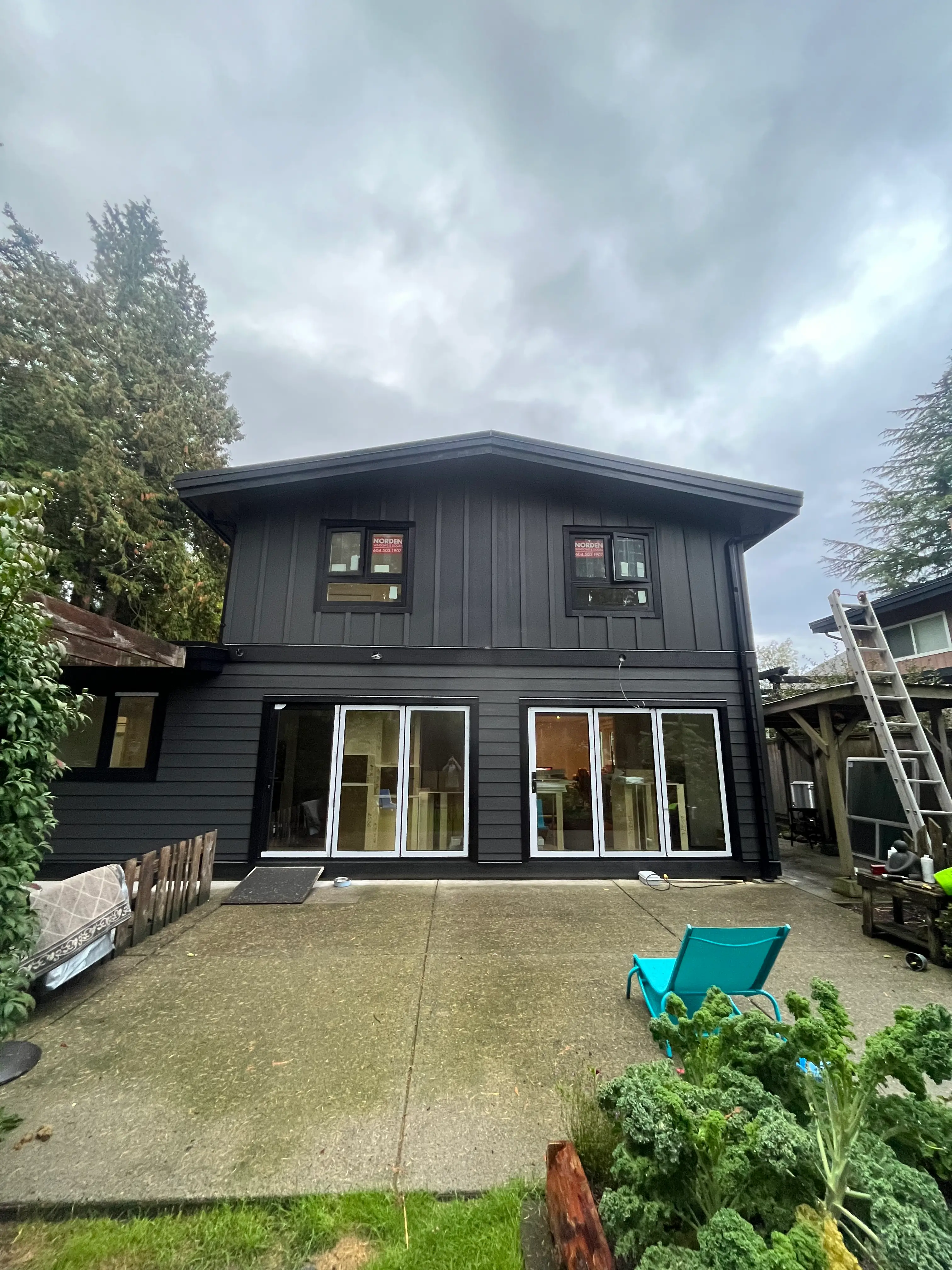 Modern black house exterior renovation with large sliding patio doors