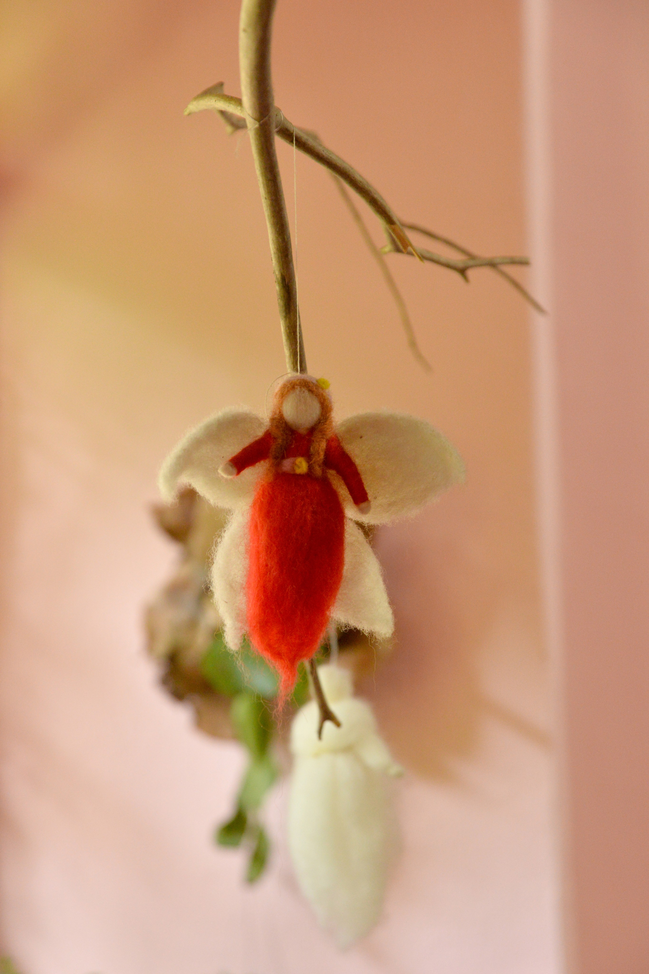 Smiling young woman with long hair standing against a dark green background, holding a finger to her chin.