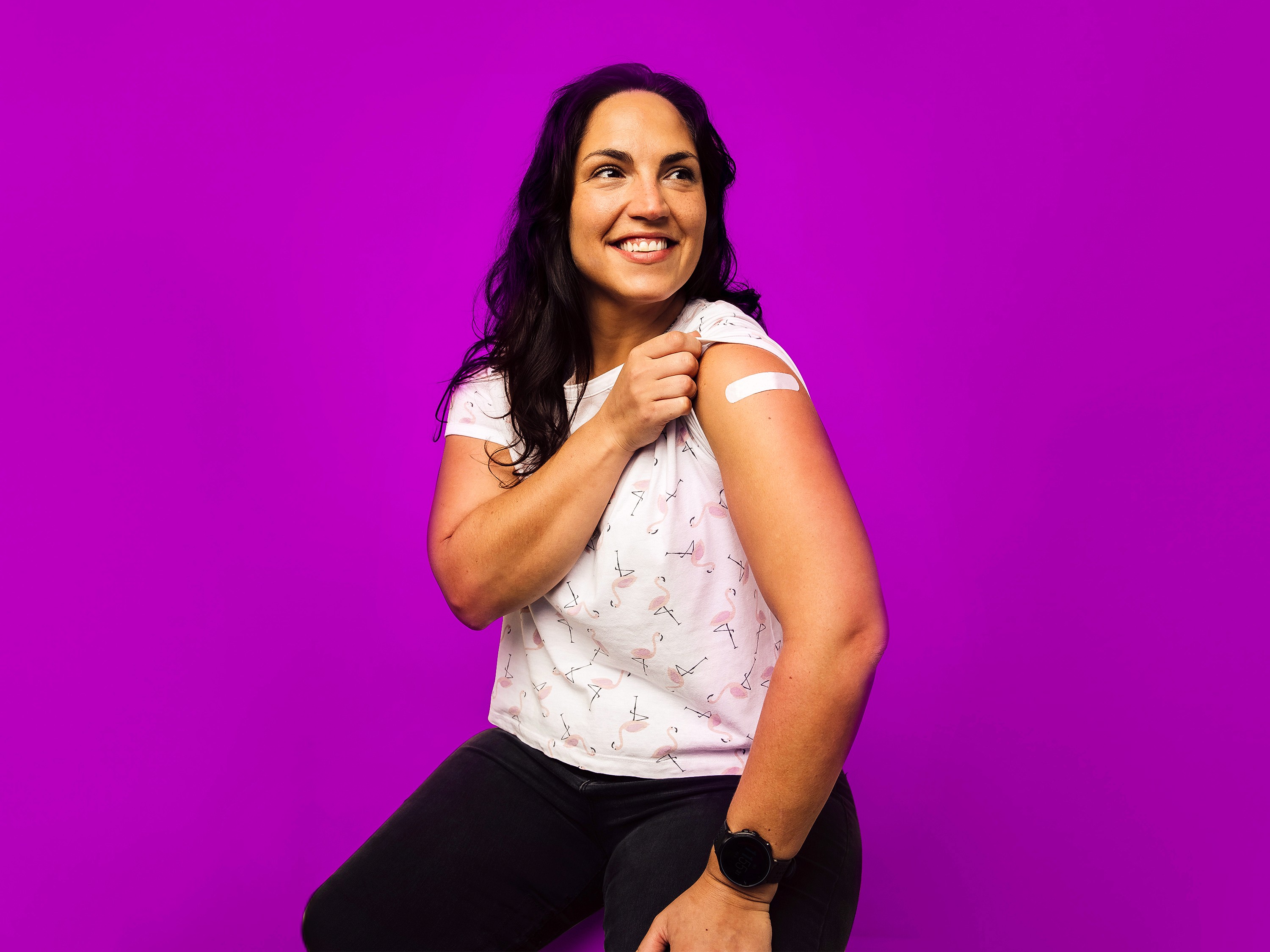 PAPEL studio headshot of Latine woman with a bandaid on her arm, with a purple backdrop.