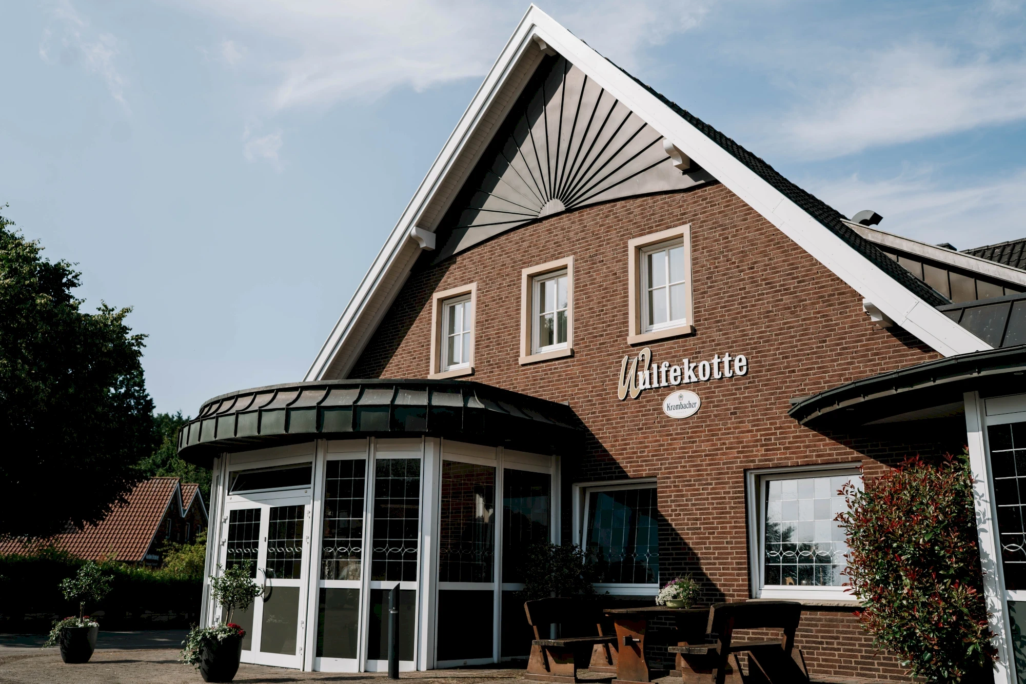 Rustikales Backsteingebäude mit dem Schriftzug "Wienkotte" neben einer Kirche mit hohem Turm.