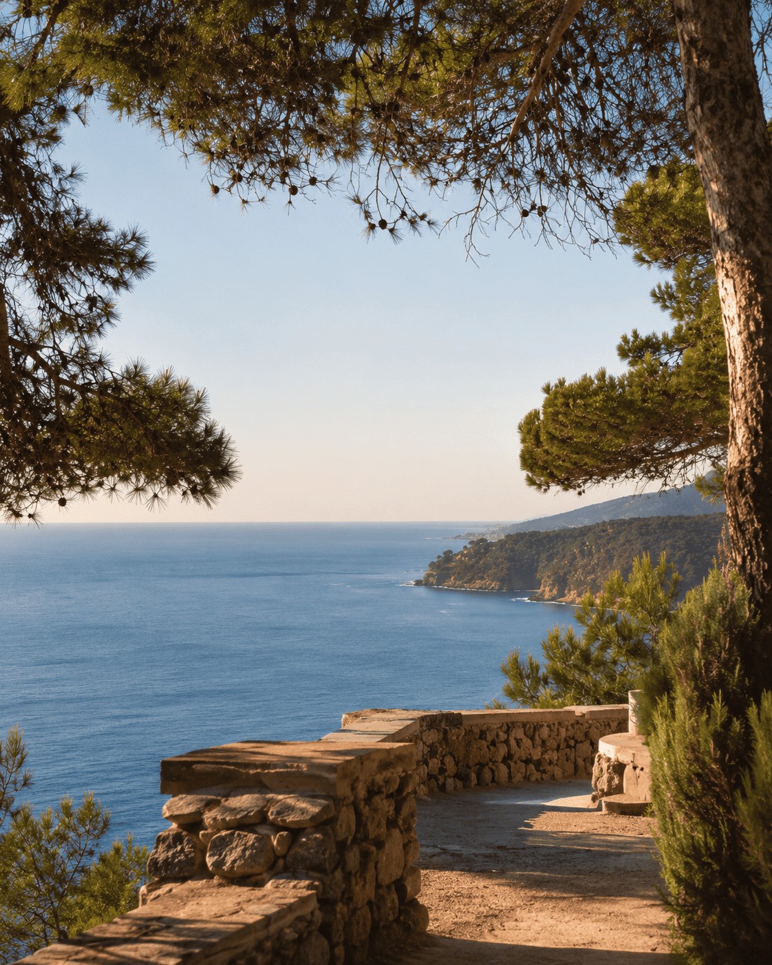 Coastal path with a rustic stone wall offering panoramic ocean views near Barcelona, showcasing the natural beauty and premium environment of Maresme.