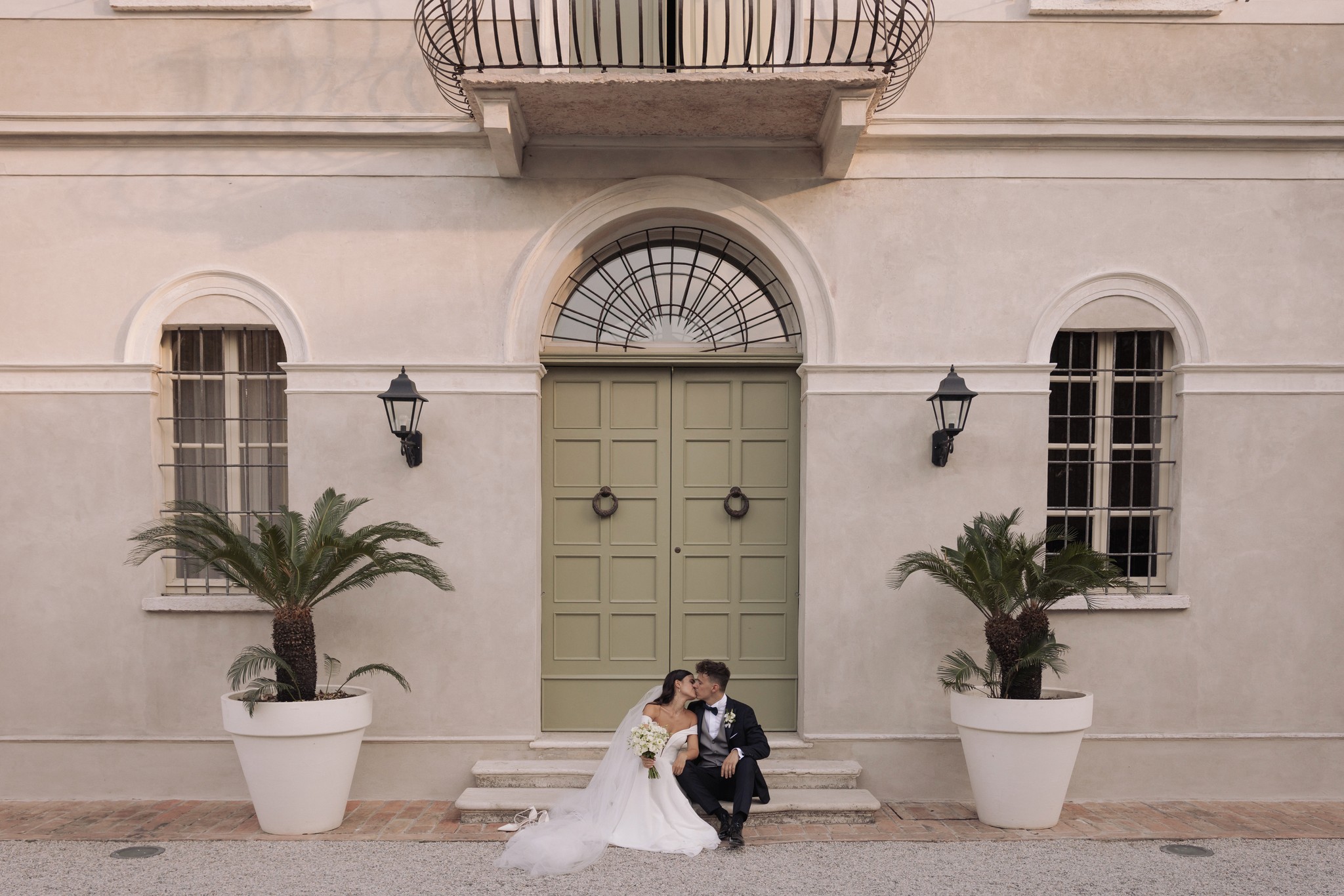 Sposi di fronte alla facciata di Villa Negri, lei in abito bianco con bouquet, reportage di matrimonio