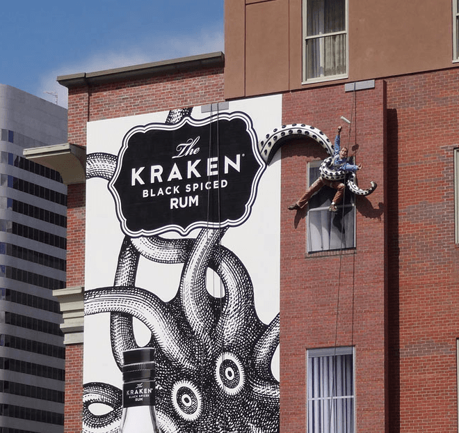 Picture of a billboard showing the Kraken, with 3D tentacle elements holding mannequins protruding from the billboard. 