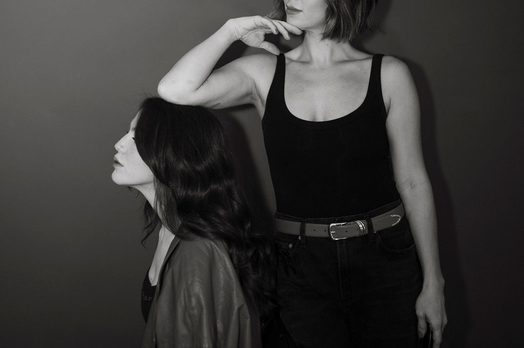 an artisitc pose with the owner of the salon resting her elbow on a clients head, faces obscrued