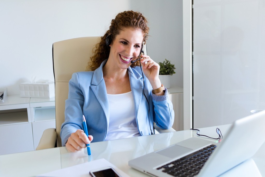 Profissional de suporte de TI utilizando headset e notebook em atendimento ao cliente, representando help desk e suporte técnico - FindUP - Help Desk
