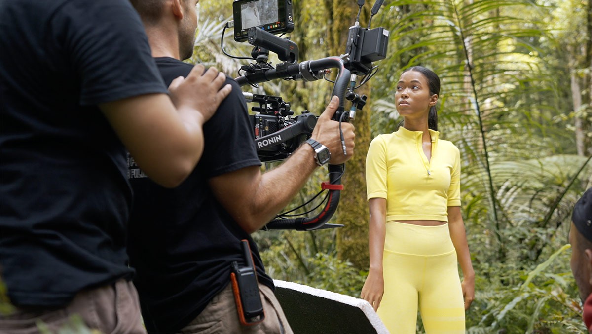 We Do Creative cinematographer operating a Ronin cinema gimbal filming a model in yellow activewear in Bali's tropical jungle during a commercial campaign shoot