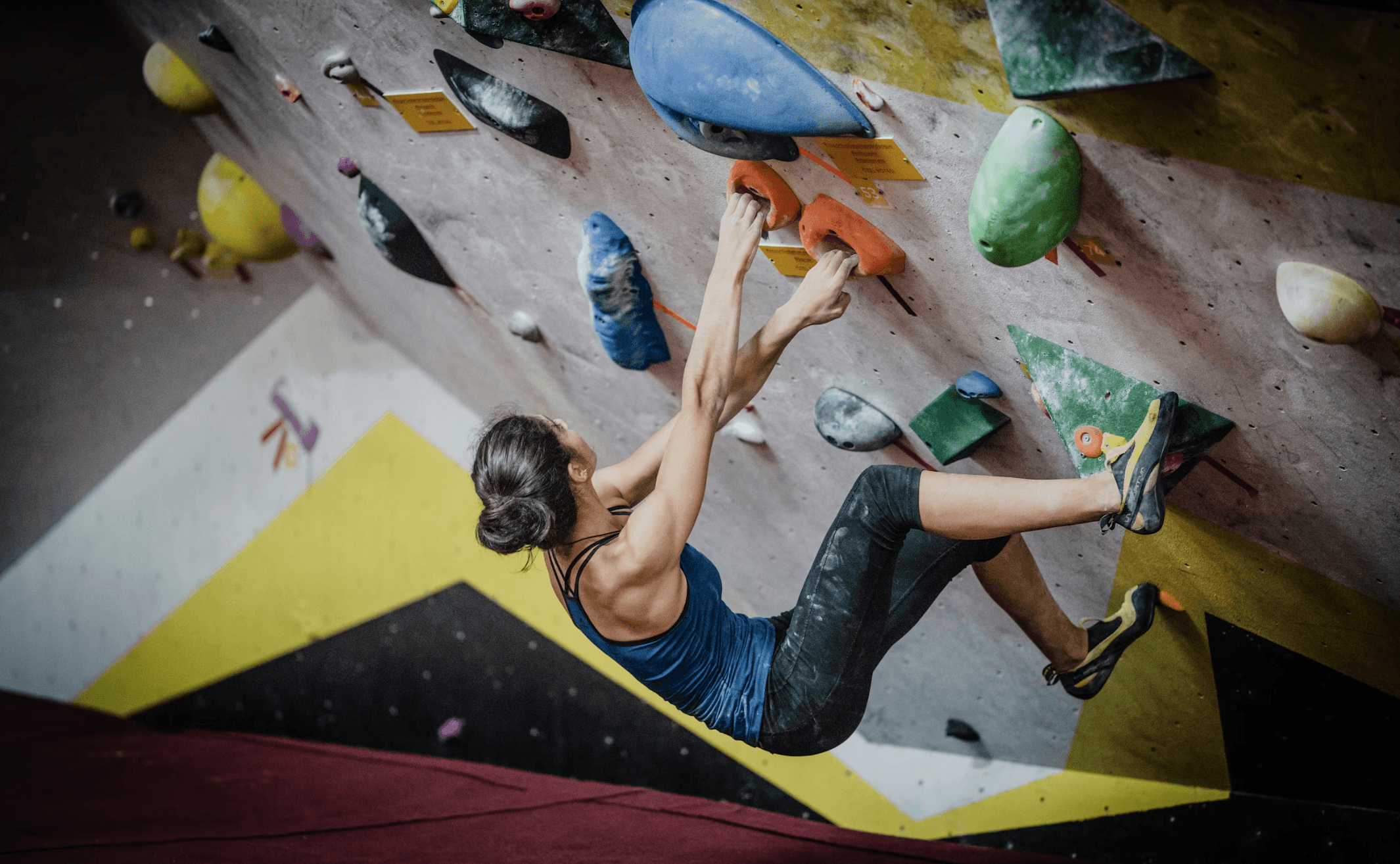 A Picture of a Lady Climbing in a Bouldering Gym