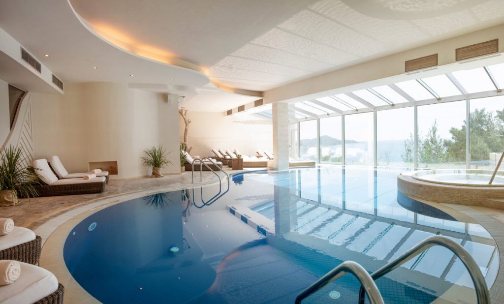 Innenansicht eines luxuriösen Schwimmbades mit Liegestühlen, Pool und Whirlpool. Entspannungsbereich für Wellnessurlaub.