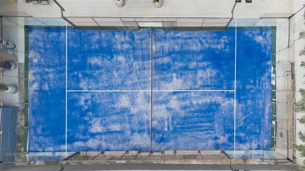 Blue padel court beside a residential tower