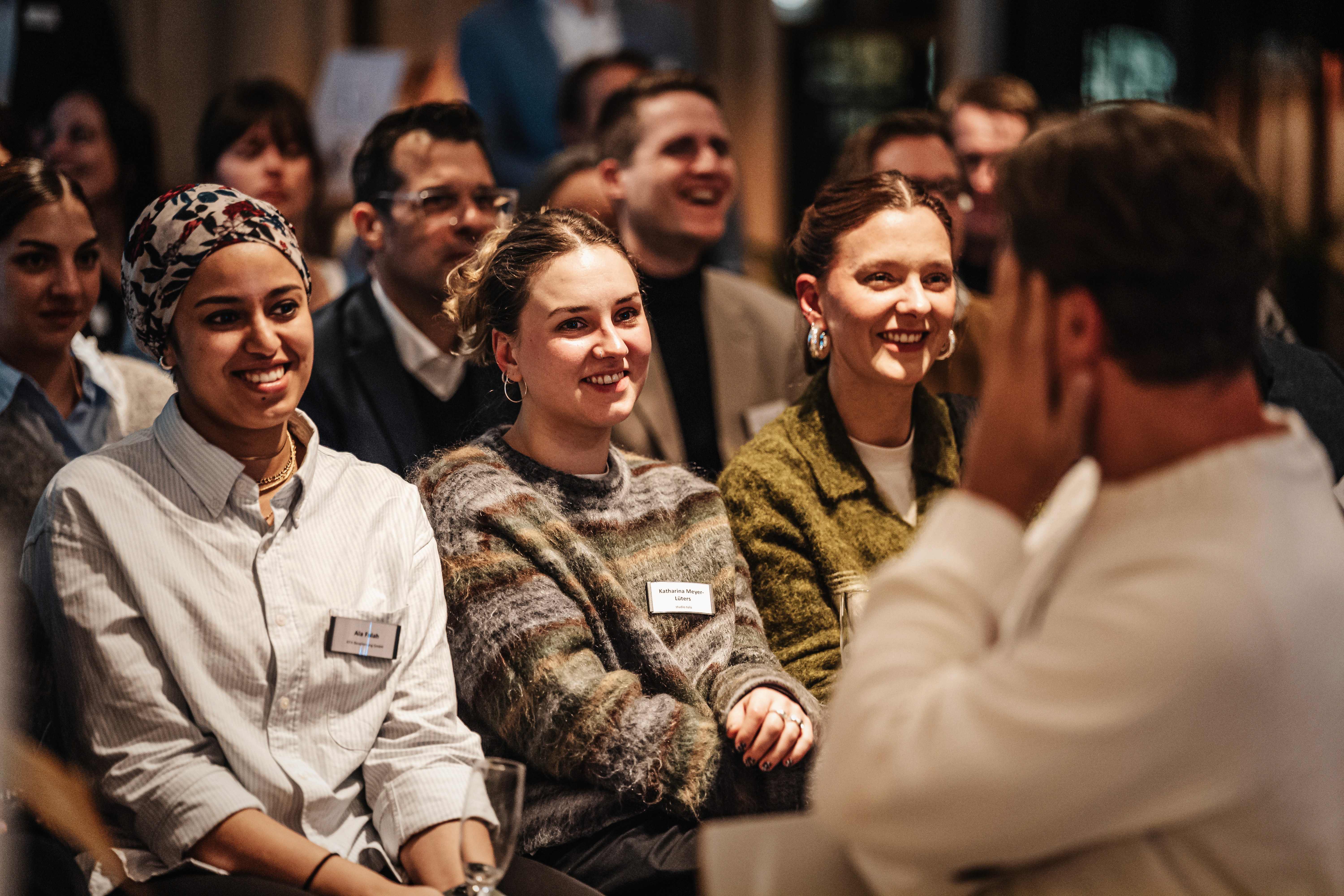 People crossing a busy street with cars and buildings.