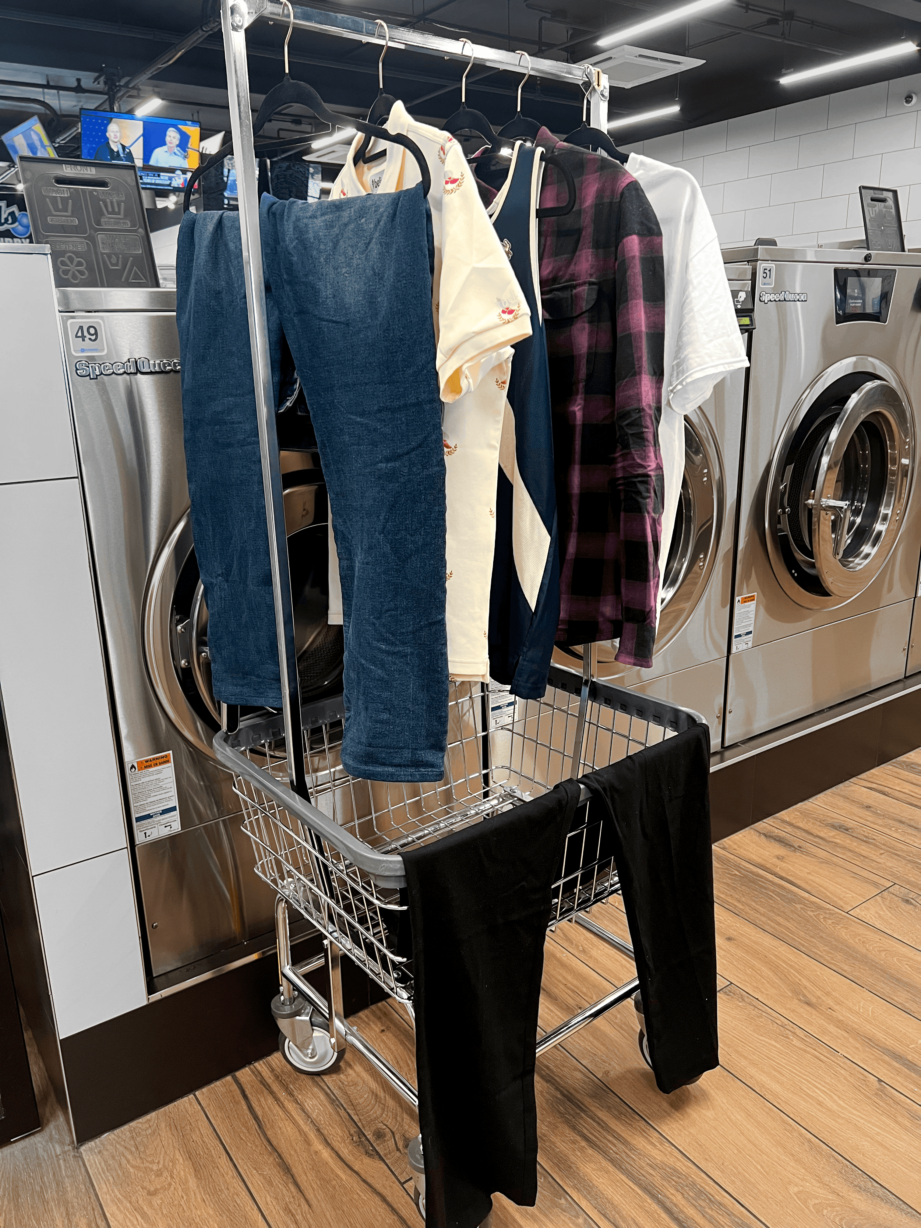 Air-dried shirts and jeans hung on hangers in a laundry cart, showcasing premium wash and fold services in a modern NYC laundromat.