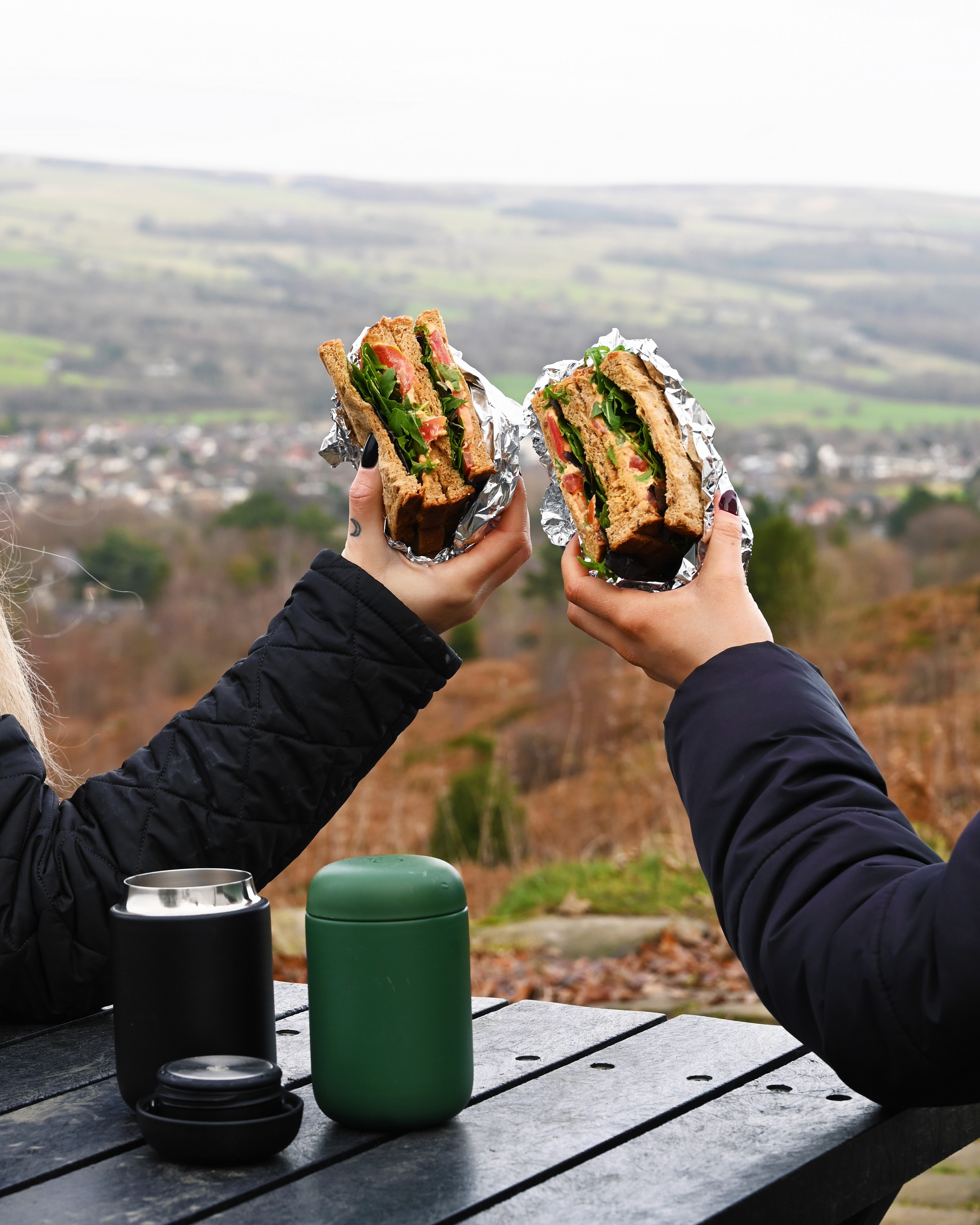 Two people cheersing sandwiches overlooking the Yorkshire Dales