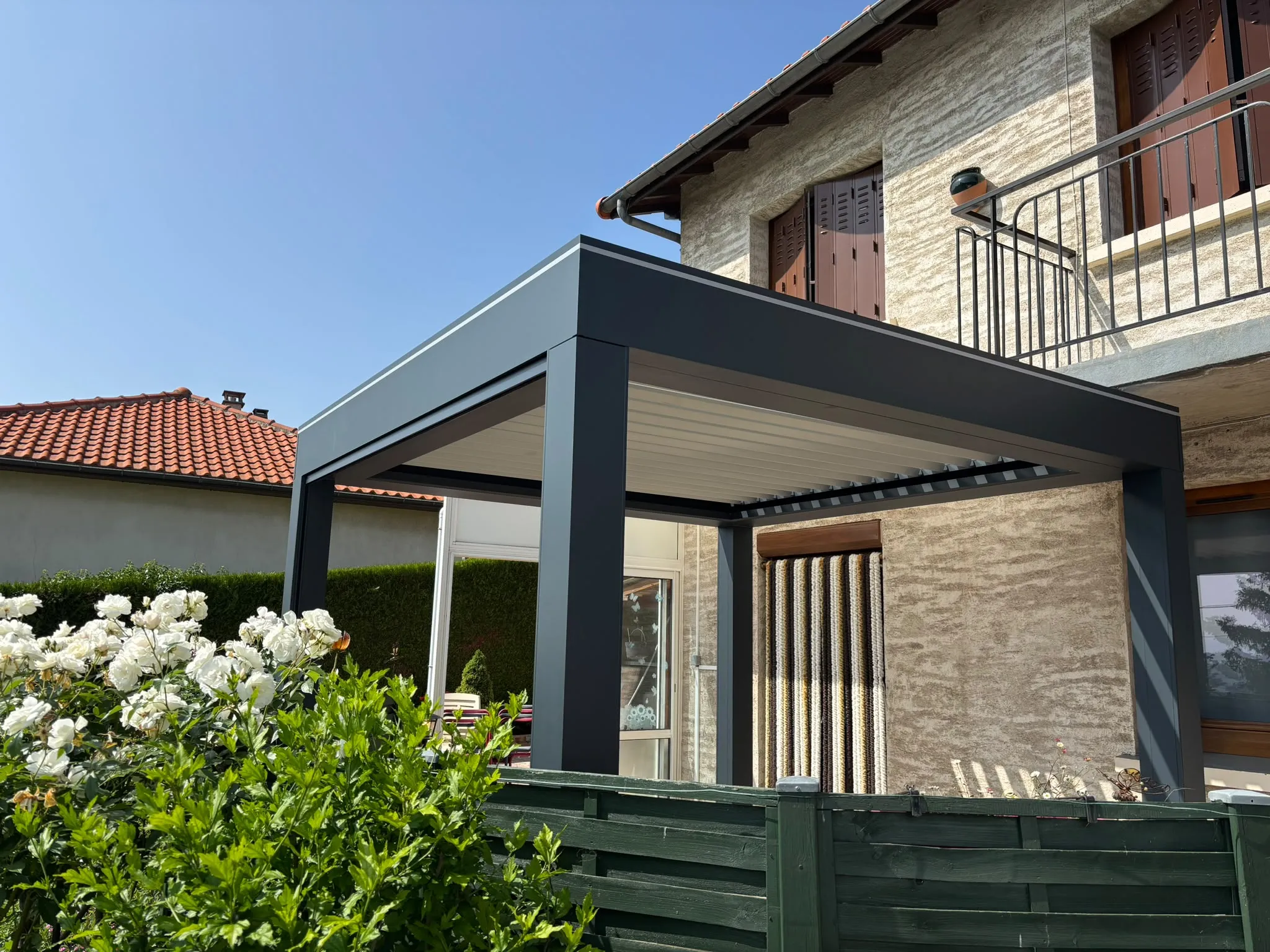 Pergola sombre adossée à une façade en pierre — AFermetures