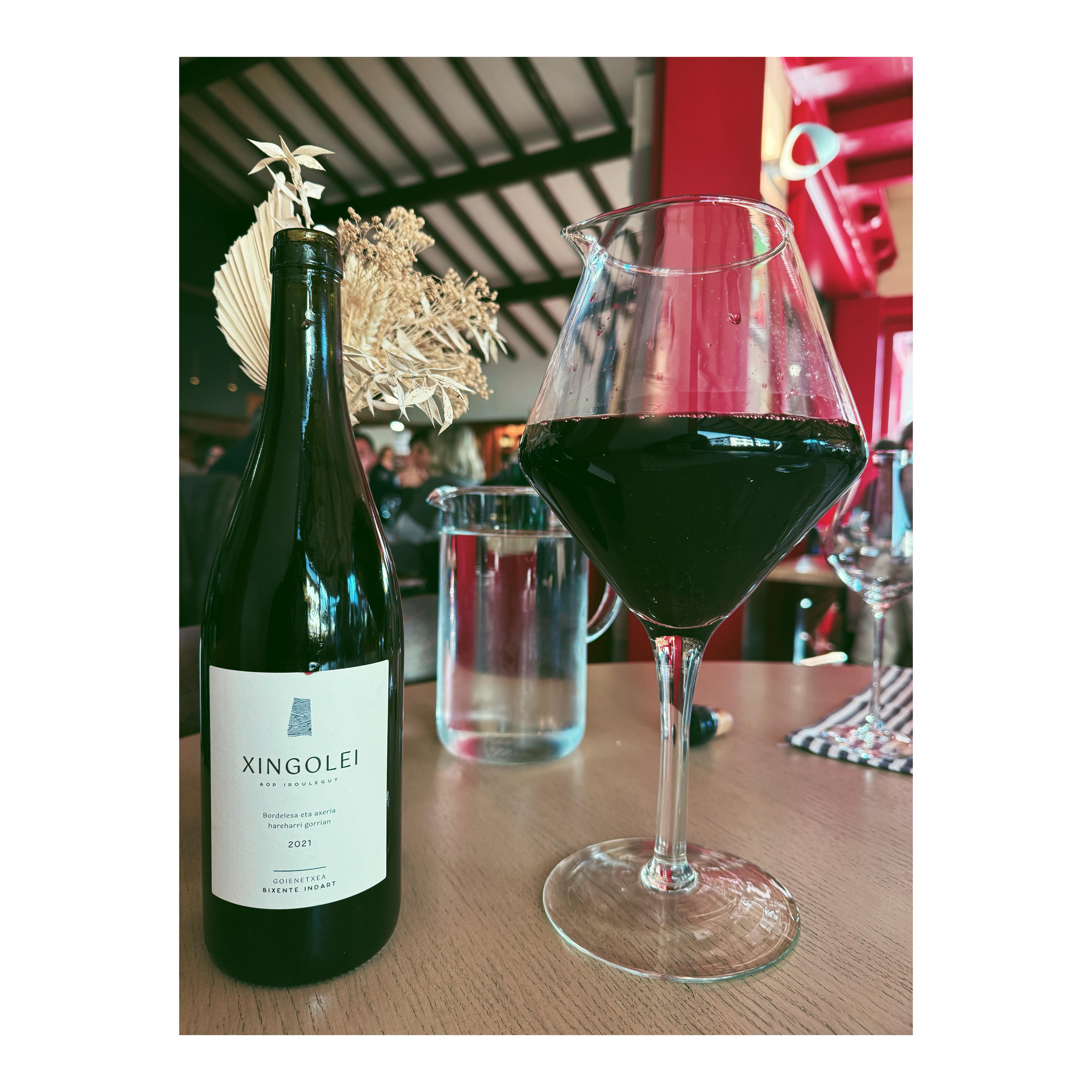 Narrow cobblestone street in a historic town, buildings with balconies on either side, archway at the end of the street.
