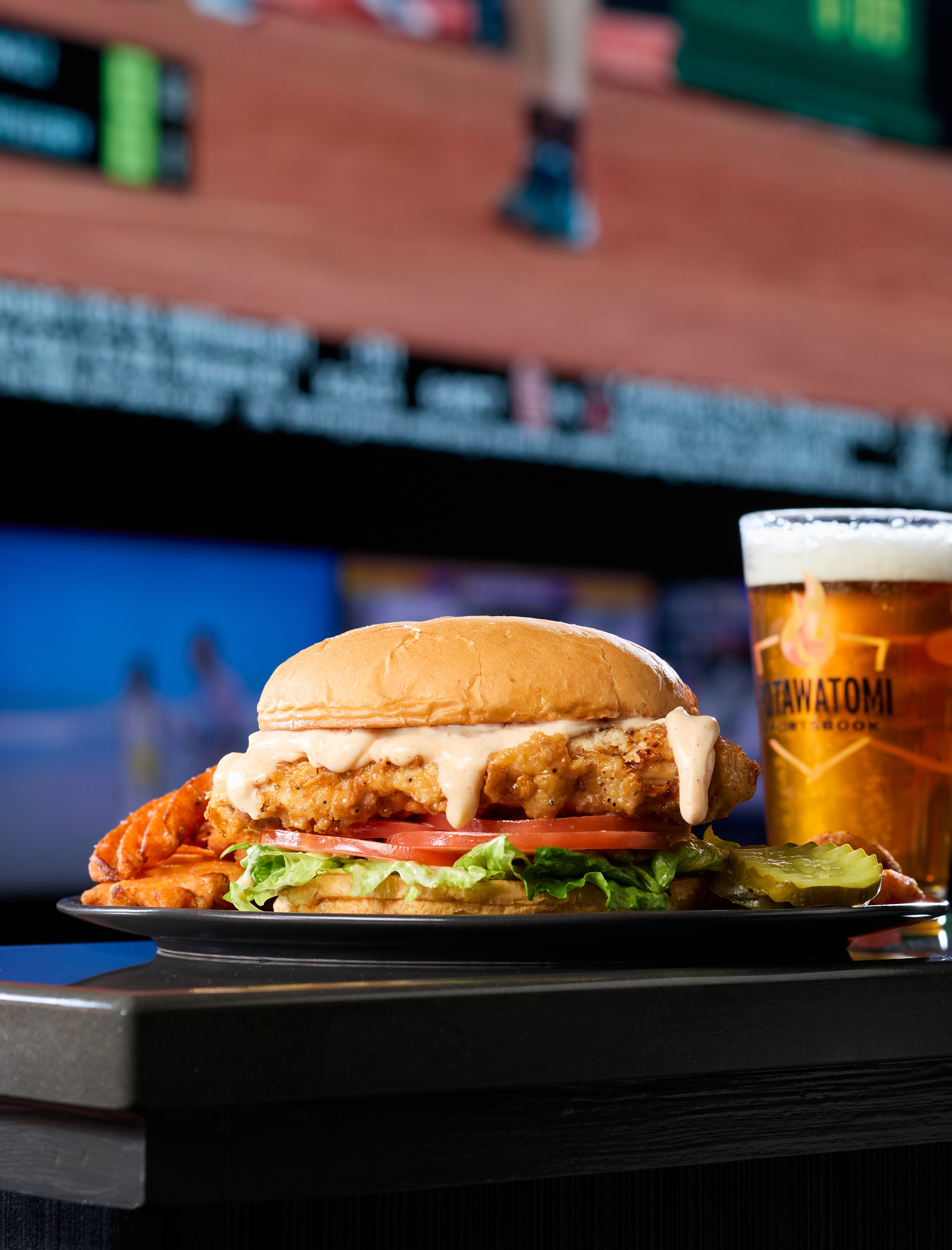 Chicken sandwich and a beer in front of a screen