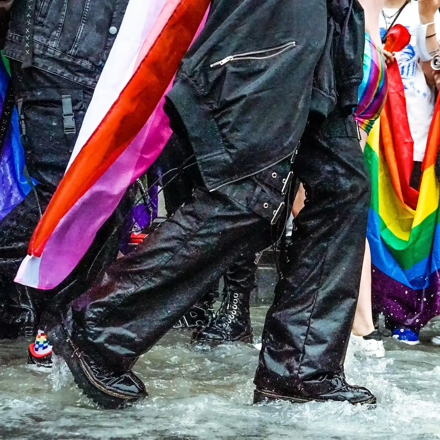 People marching with LGBTQ+ pride flags at a parade in NYC, symbolizing lesbian affirming therapy, community support, and inclusive psychotherapy.