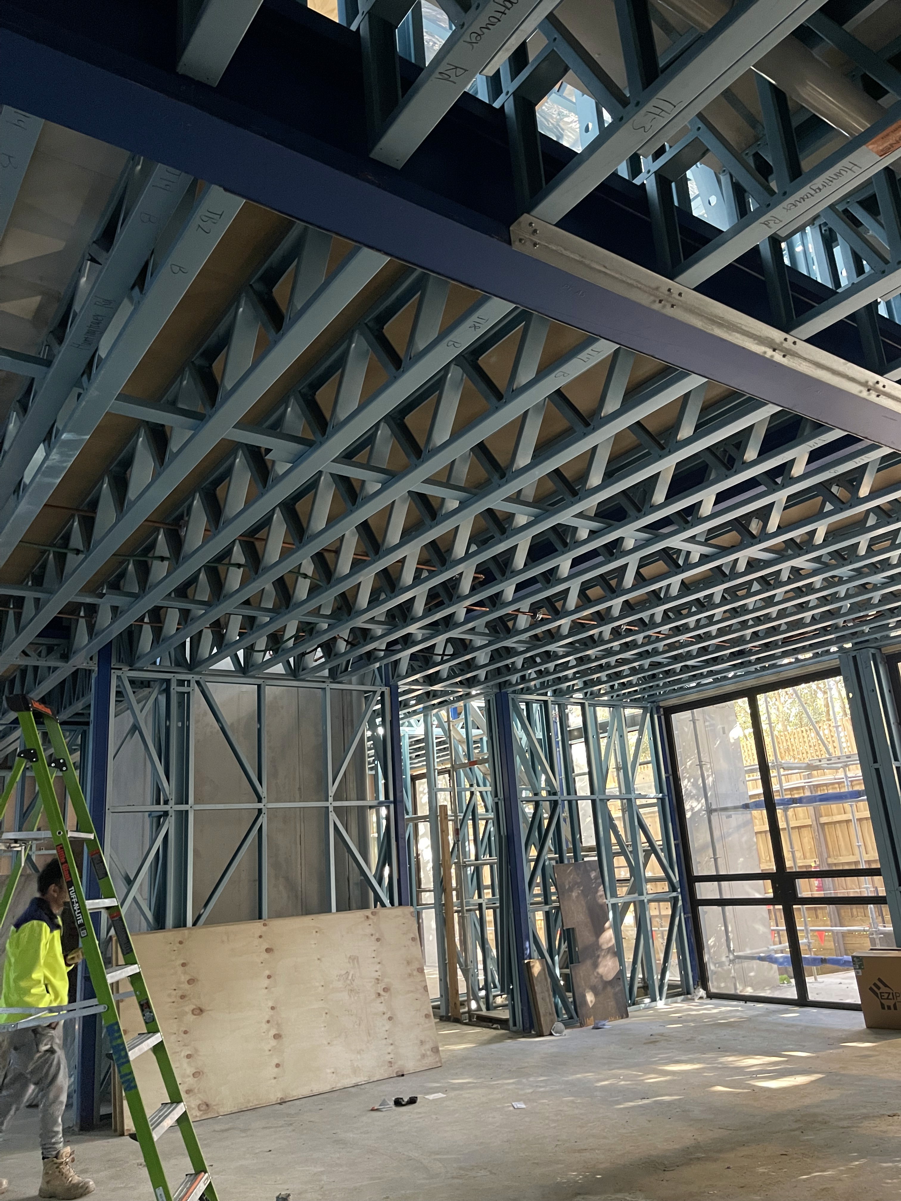 A serene outdoor seating area with two chairs, surrounded by lush greenery and a glassed-in structure.