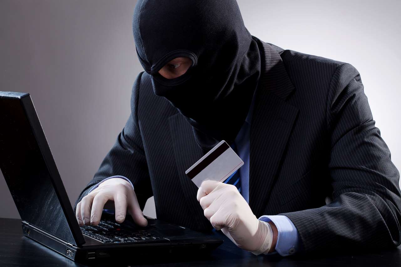 Homem encapuzado e de preto fazeno alusão a fraudes bancárias pela Internet