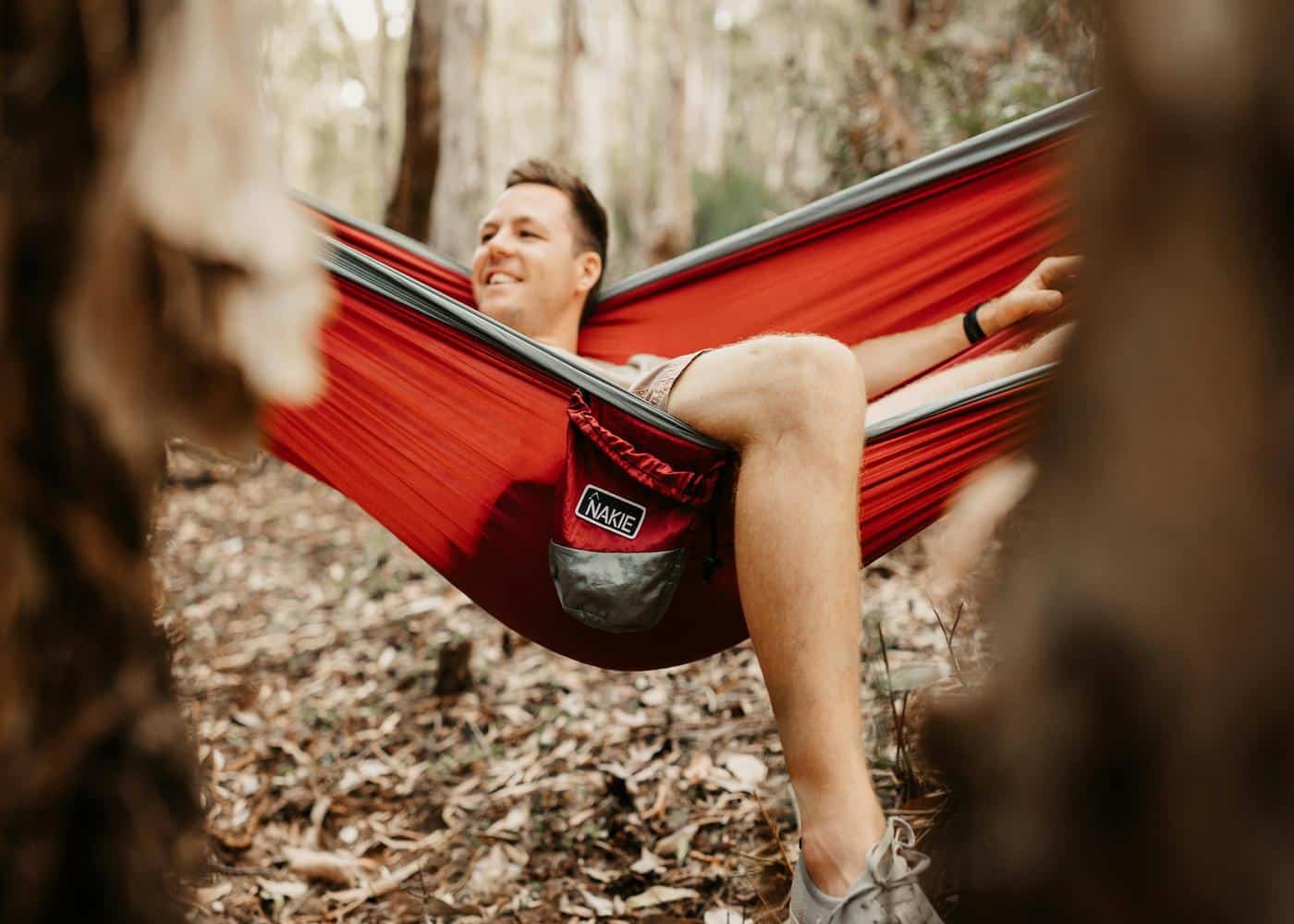 Smiling man laying on a red hammock