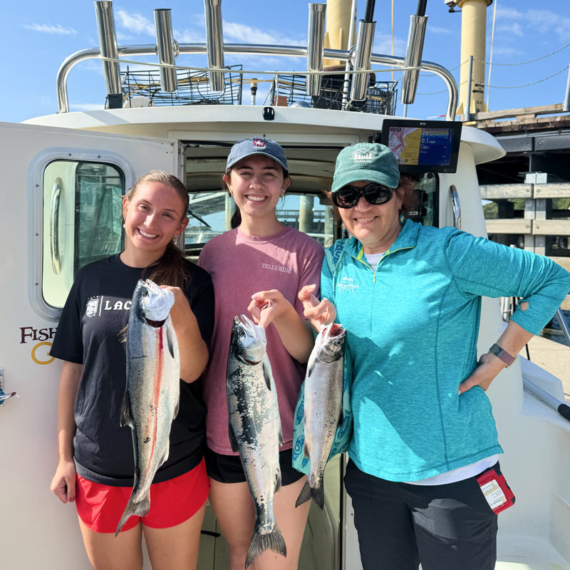 Three ladies holding freshly caught salmon