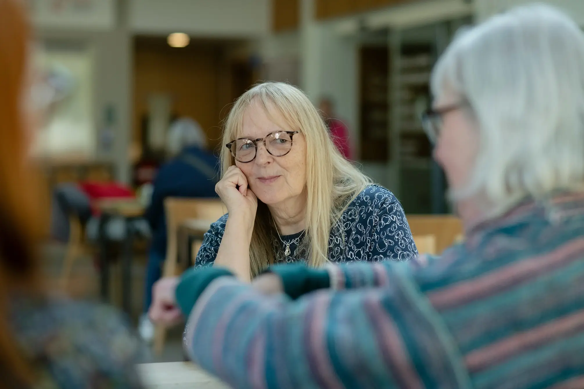 a woman sitting at a table talking to another woman
