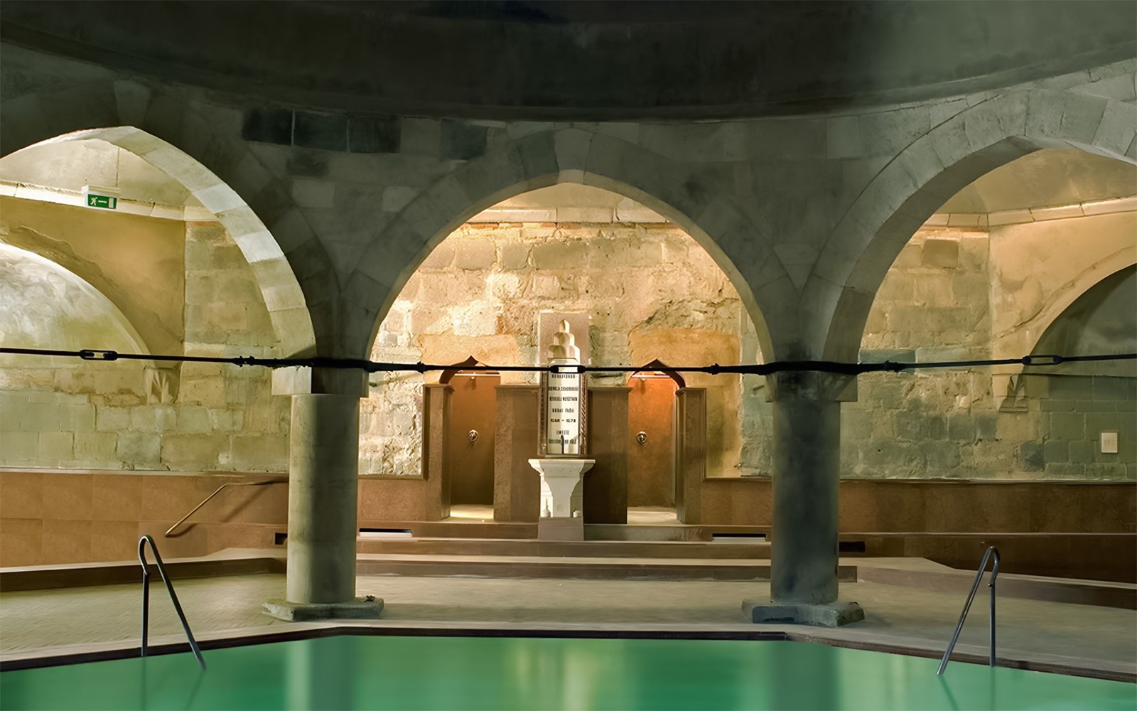 Rudas Thermal Spa interior with arches and pool at night.