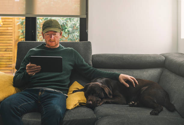 Man on ipad with his dog on sofa, The Shelter MK