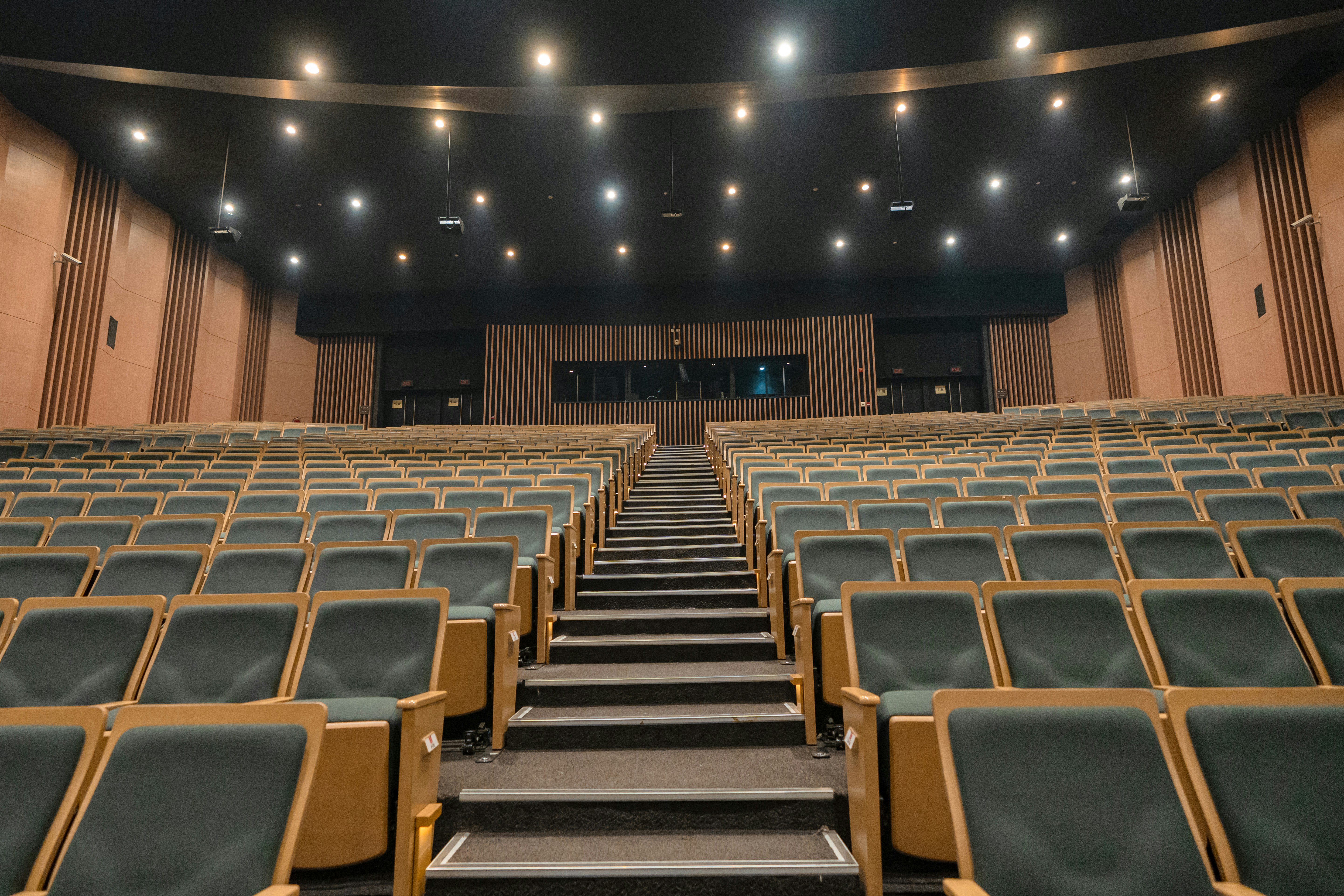Empty theater seats with a central aisle and stage.