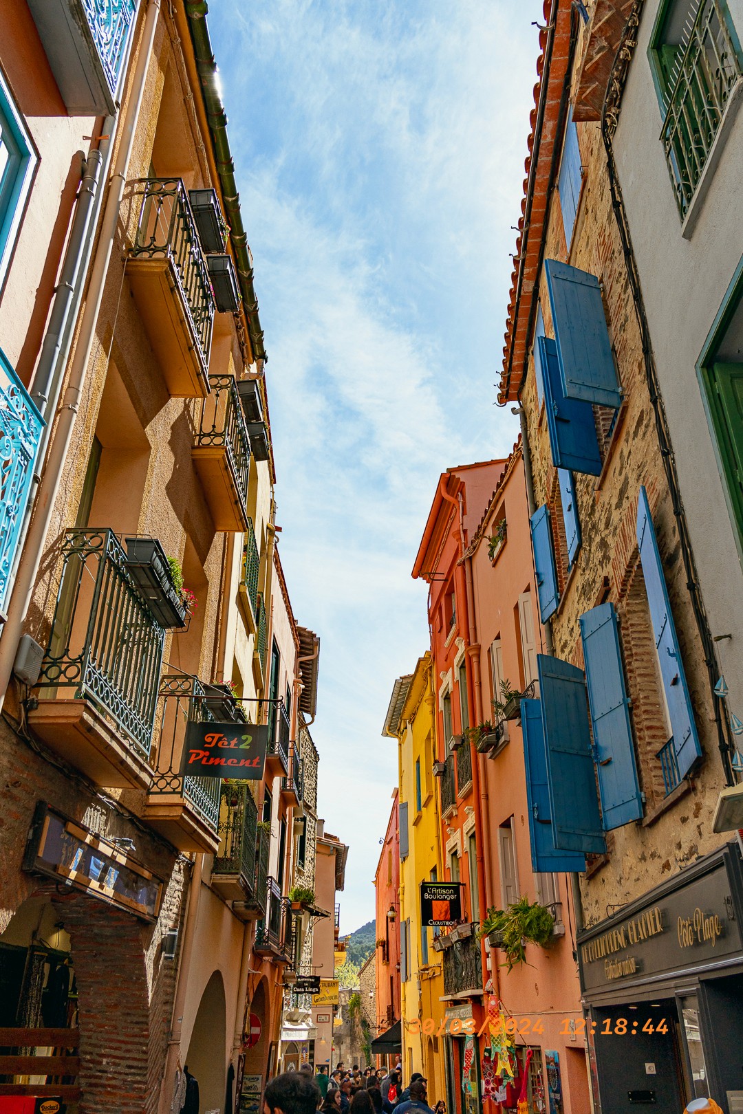 Ruelle étroite aux façades colorées, volets bleus et balcons.