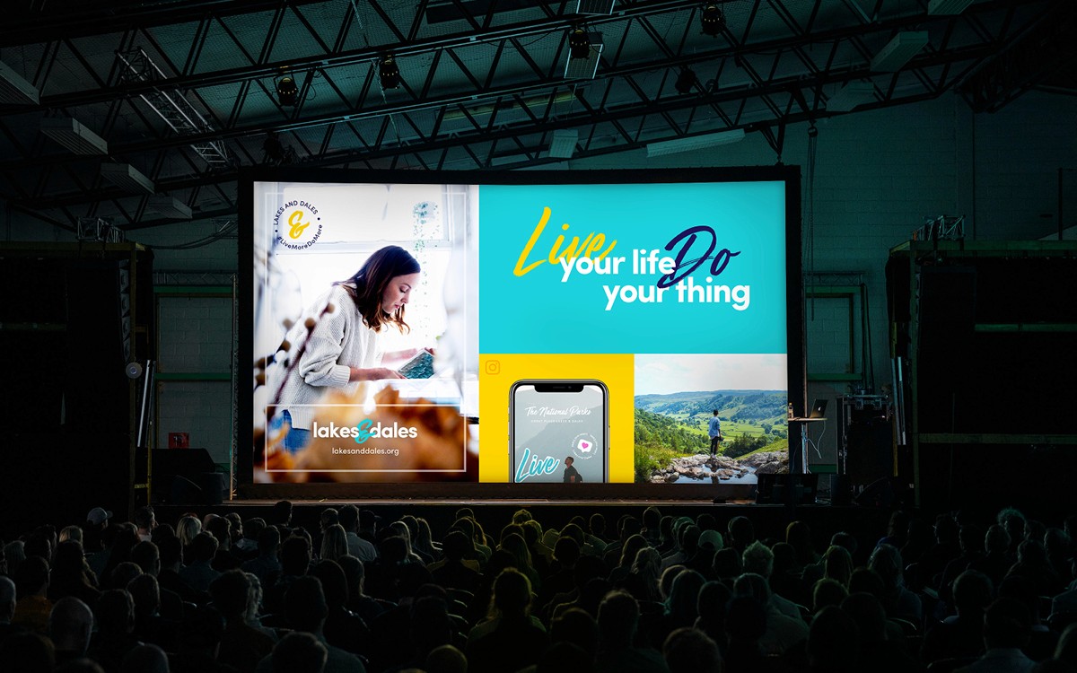 Large presentation screen in a hall filled with people