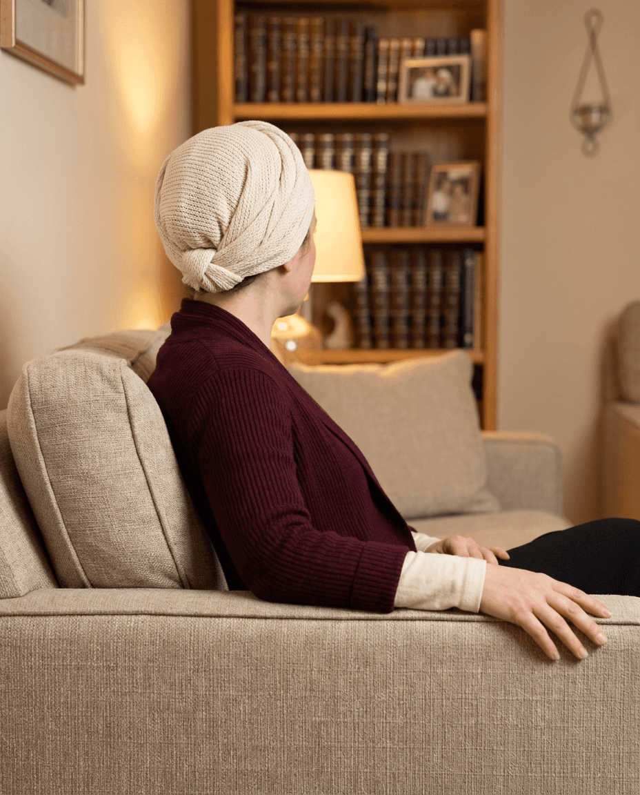 A person with curly hair sits at a desk, working on a laptop in a cozy, well-lit environment.