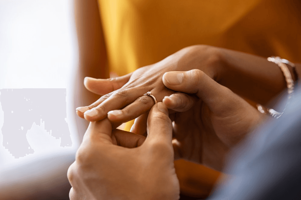 A close-up of two hands, one placing a ring on the other's finger, suggesting a moment of connection or commitment.
