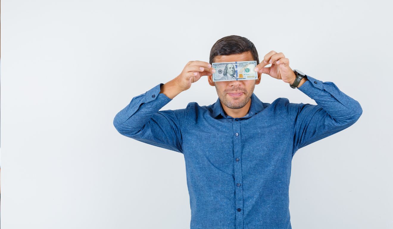 Imagem mostra homem segurando uma nota de dinheiro na frente dos olhos