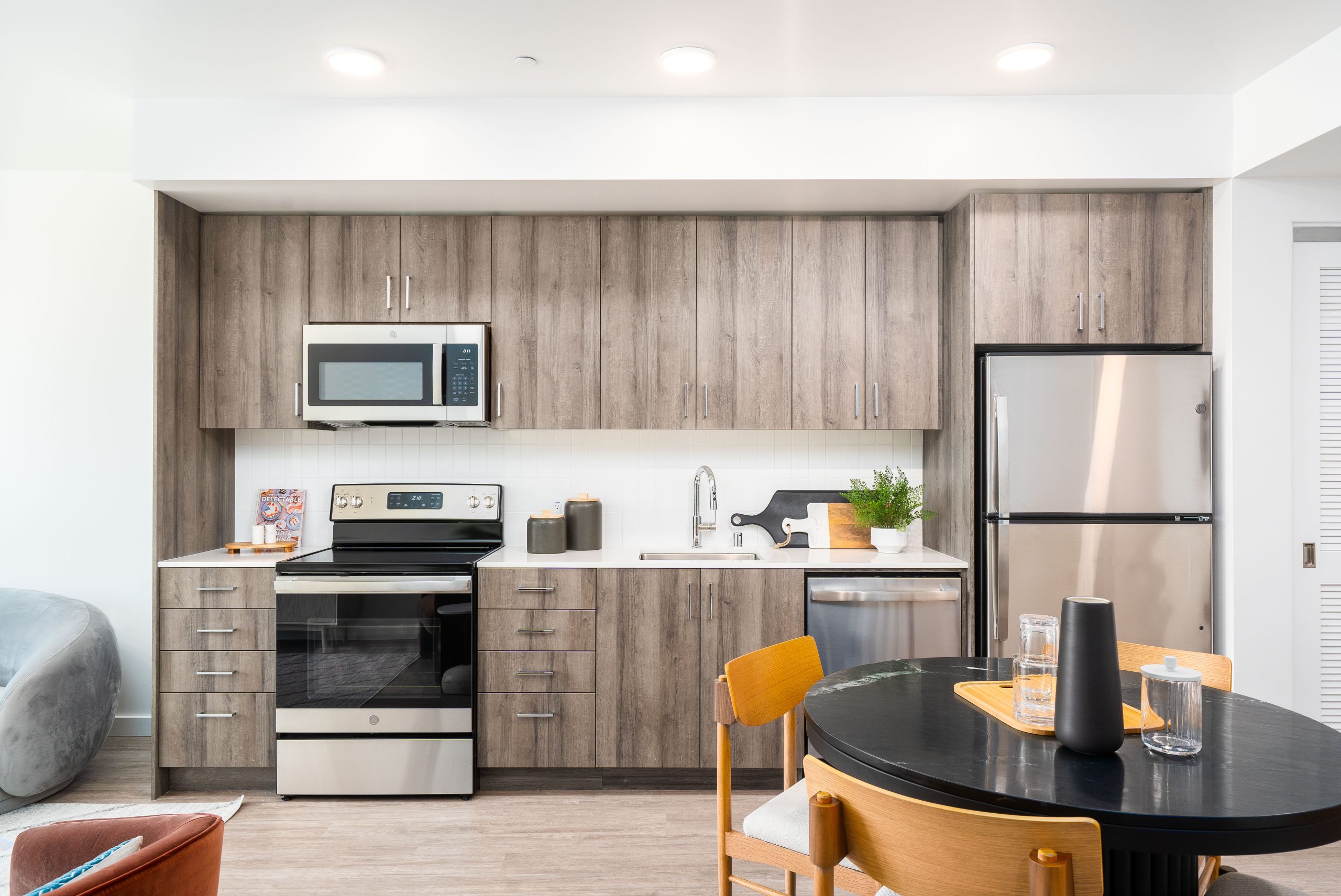 Chic apartment residences with modern design, large glass facades, and a backdrop of trees and city life.