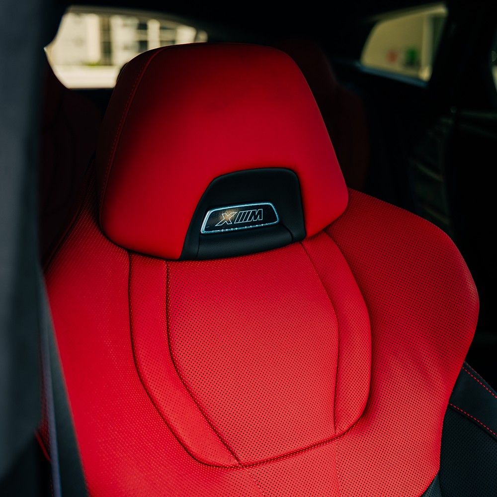 Luxurious rear seat of the red BMW XM, showcasing its red and black Merino leather upholstery and comfortable design.
