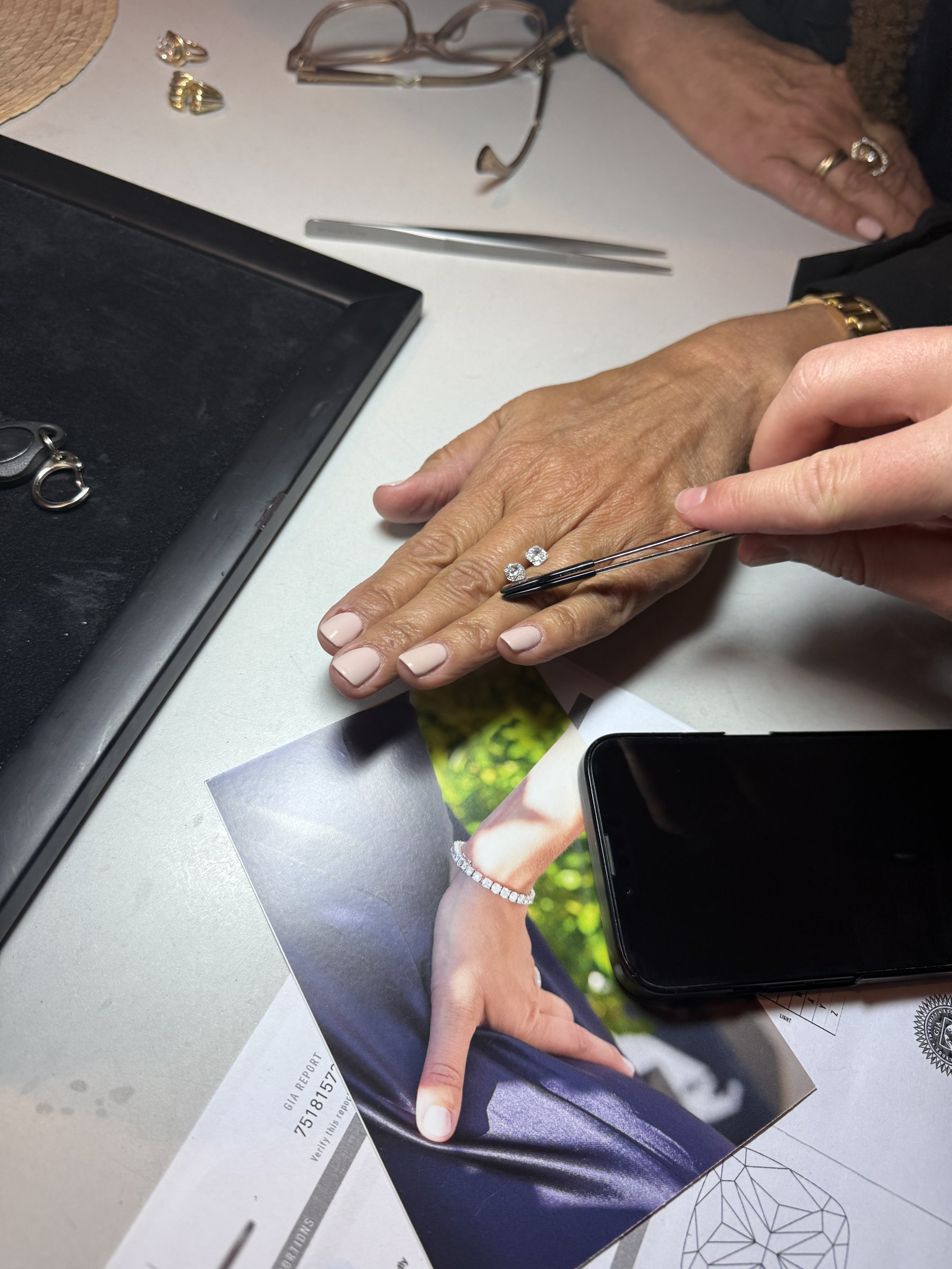 Hånd med en lille diamant i pincet ved siden af en gradingrapport