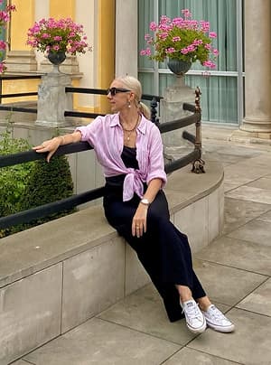 Black-and-white portrait of a man with an afro in motion, wearing a hoop earring and chain necklace, against a light gray background.
