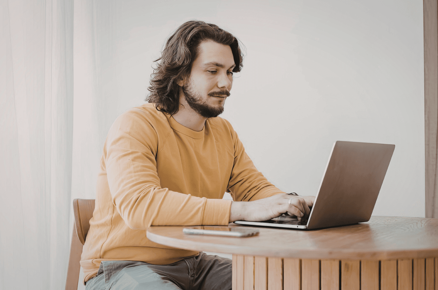 Man working on a laptop at a table, representing analysis of mobile vs desktop conversion behavior in Amazon PPC campaigns.