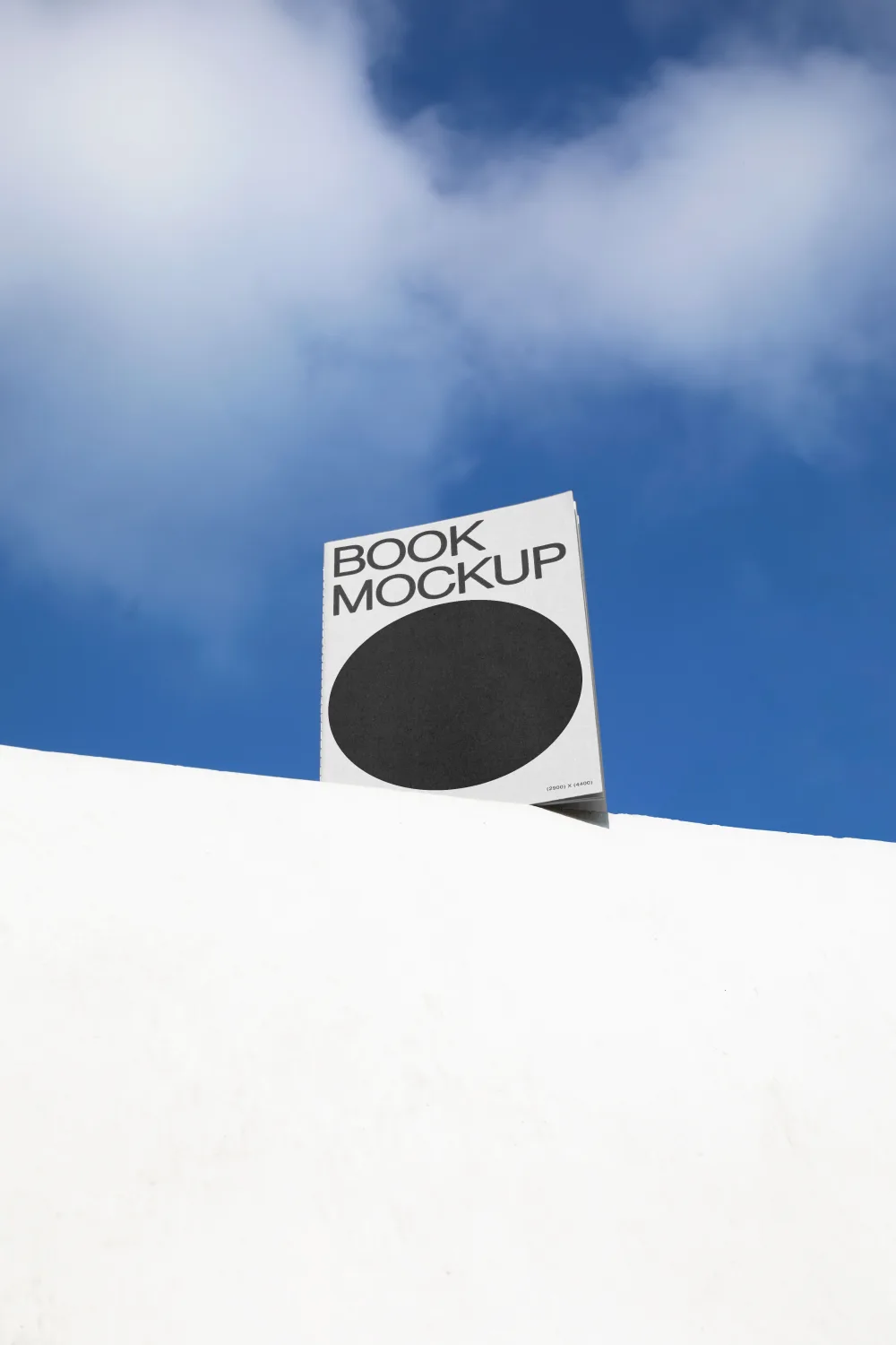 A book mockup with a black cover and minimalist design, propped against a white surface, set against a vibrant blue sky with scattered clouds for a clean and modern presentation.
