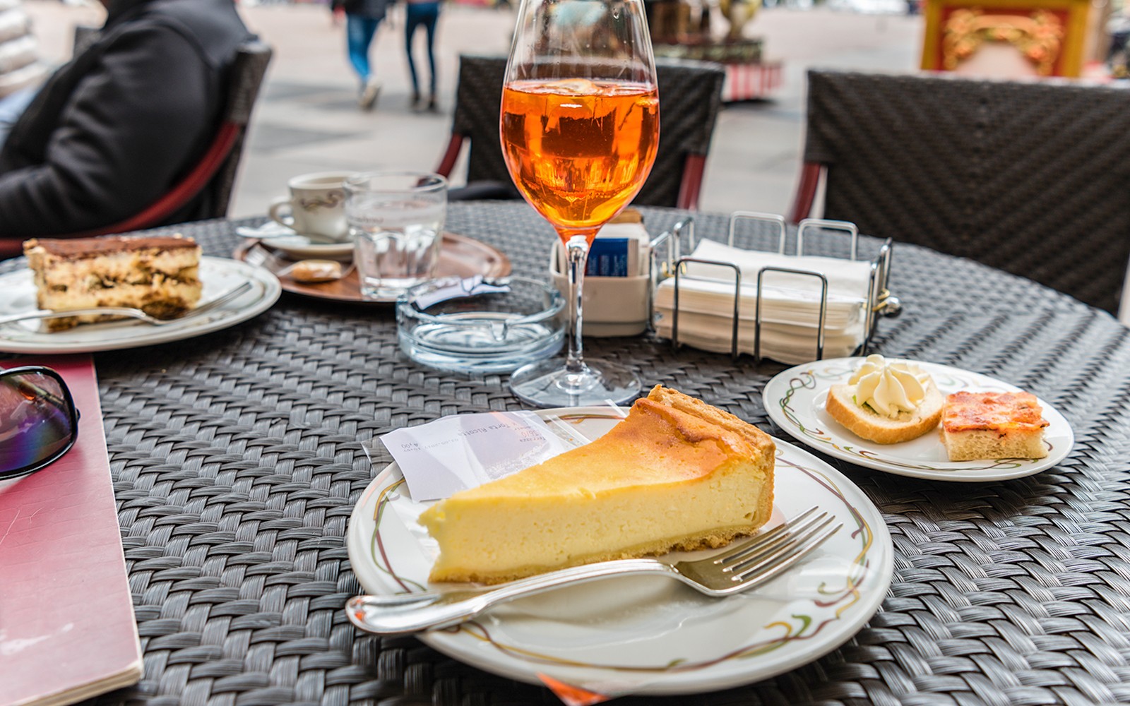 Tiramisu en cheesecake op een cafétafel met een glas Aperol Spritz.